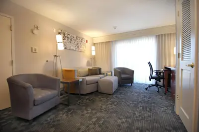 a hotel room with a couch and chairs and a desk at Courtyard by Marriott Merced in Merced