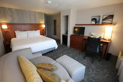 a hotel room with a bed and a couch at Courtyard by Marriott Merced in Merced