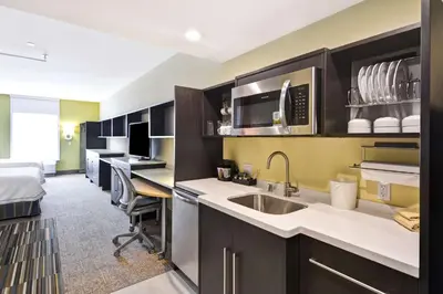 a kitchen with a sink and a bed in a room at Home2 Suites By Hilton Hanford Lemoore in Hanford