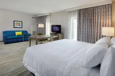 a bedroom with a white bed and a blue couch at Hampton Inn & Suites Sacramento at CSUS in Sacramento