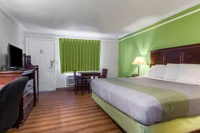 a hotel room with a bed and a green wall at Motel 6-Kingsburg, CA in Kingsburg
