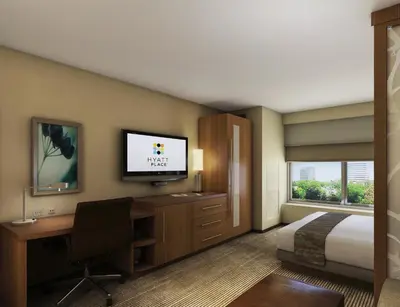 a hotel room with a bed and a desk and a television at Hyatt Place Delano in Delano