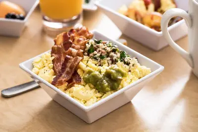 a bowl of scrambled eggs with bacon and other food at Hyatt Place Delano in Delano