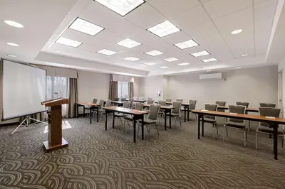 a conference room with tables and chairs and a screen at Hampton Inn & Suites Tulare in Tulare
