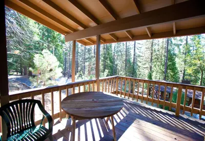 a wooden porch with a wooden table and chairs on it at 24B Birds Eye View in Wawona