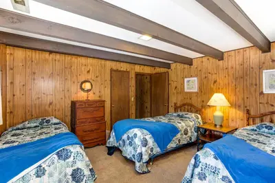 two beds in a room with wooden walls at 24B Birds Eye View in Wawona