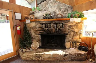 a stone fireplace in a living room with a fire place at 6B Meadow View in Wawona