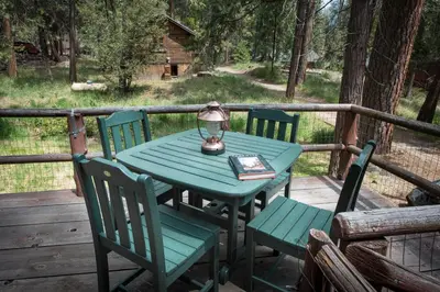 a green table with chairs and a lamp on a deck at 14 Chipmunk Hollow in Wawona