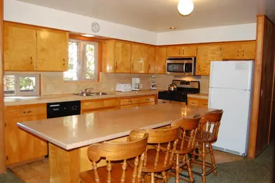 a kitchen with a white refrigerator and wooden cabinets at 99 Yosemite Mountain Lodge in Wawona