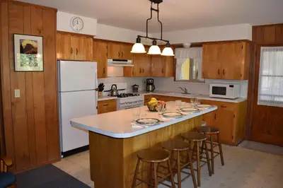 a kitchen with wooden cabinets and a island with bar stools at 11B Sequoia House in Wawona
