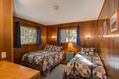 a bedroom with two beds and a table and two windows at 11B Sequoia House in Wawona