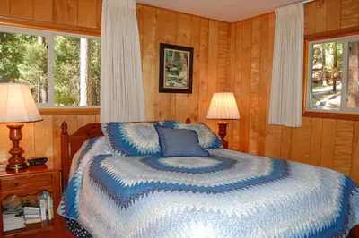 a bedroom with a bed and two lamps and two windows at 39 River Song in North Wawona