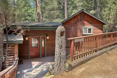 a log cabin with a porch and a red door at 1L The Tree House in North Wawona
