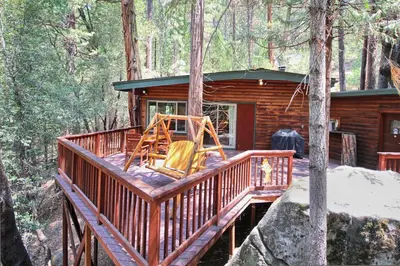 a log cabin in the woods with a swing at 1L The Tree House in North Wawona