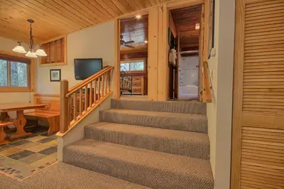 a staircase in a cabin with a television and a table at 1L The Tree House in North Wawona