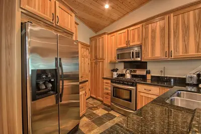 a kitchen with wooden cabinets and a stainless steel refrigerator at 1L The Tree House in North Wawona