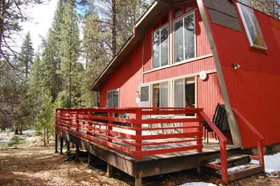 a red house with a red railing on the porch at 46R Manzanita Lodge in Wawona