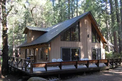 a cabin in the woods with chairs on a deck at 50 Spindlers Chalet in Wawona