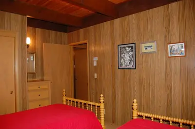 a bedroom with a red bed and wooden walls at 50 Spindlers Chalet in Wawona