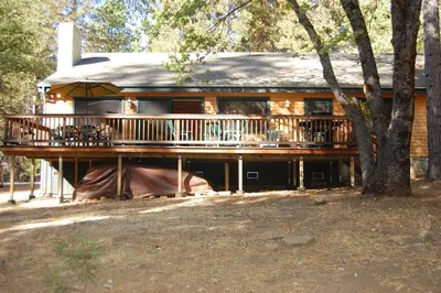 a large house with a large deck in the woods at 9N Fox Hollow in Wawona