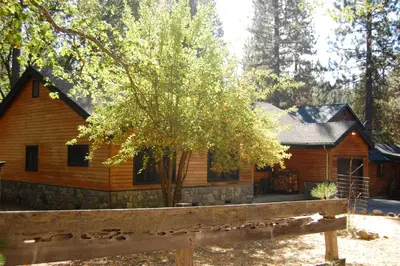 a log cabin with a fence in front of it at 9N Fox Hollow in Wawona