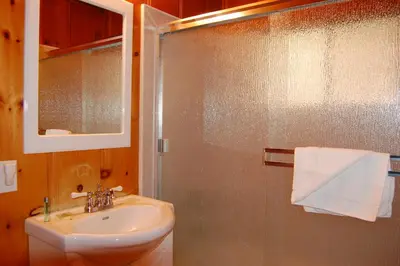 a bathroom with a sink and a shower with a mirror at 76 Howards Retreat in North Wawona