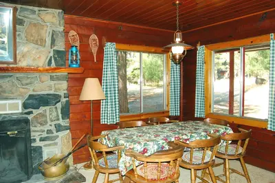a dining room with a table and chairs and a stone wall at 3N Lockwood Lodge in Wawona