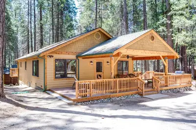 a cabin in the woods with a large deck at 36 Larkspur Lair in Wawona
