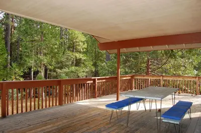 a wooden deck with a table and chairs on it at 43A Mountain Retreat in Wawona