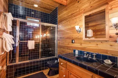 a bathroom with a sink and a glass shower at 41A Cedar Chalet in Wawona