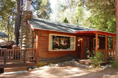a small log cabin with a porch and a window at 18 Le Fawn in North Wawona