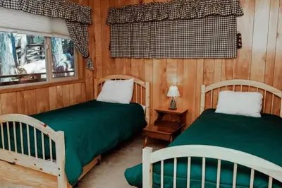 two beds in a room with wooden walls at 19B Yosemite Retreat in the Meadows in Wawona