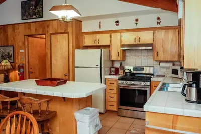 a kitchen with wooden cabinets and a white refrigerator at 19B Yosemite Retreat in the Meadows in Wawona