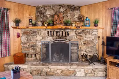a stone fireplace in a living room with a tv at 4 Pine Creek Cabin in North Wawona