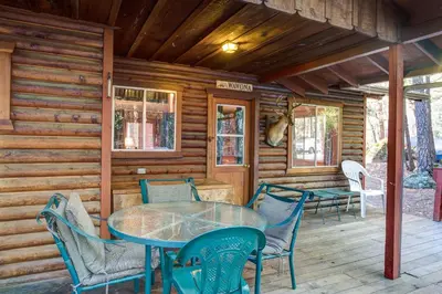 a dining room with a table and chairs on a porch at 4 Pine Creek Cabin in North Wawona