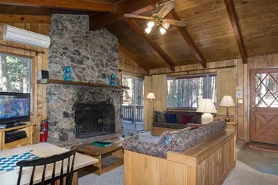 a living room with a couch and a stone fireplace at 23B Robins Nest in North Wawona
