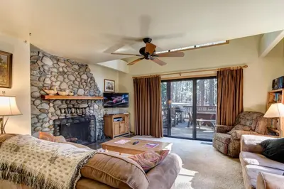 a living room with a couch and a stone fireplace at 12 Cabin Twelve in Wawona