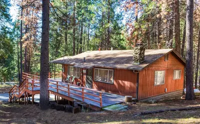 a house in the woods with a large deck at 9B Deer Hollow in Wawona