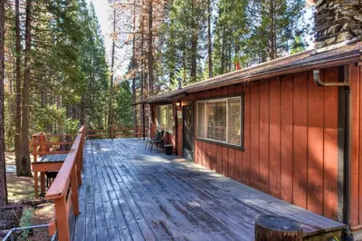 a wooden deck next to a cabin in the woods at 9B Deer Hollow in Wawona