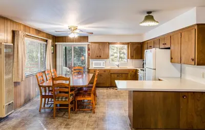 a kitchen with wooden cabinets and a table and chairs at 9B Deer Hollow in Wawona