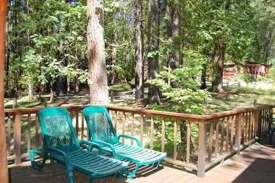 two green chairs sitting on a deck with trees at 93R Deer Lodge in North Wawona