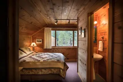 a bedroom in a log cabin with a bed and a sink at 37 Wapiti in North Wawona