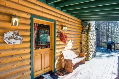 a wooden cabin with a door and a porch at 21 River Refuge in North Wawona