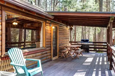 a cabin with a deck with a grill and chairs at 51 Mia Mora in Wawona
