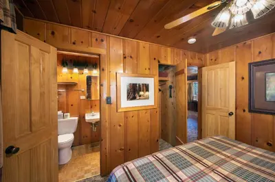 a bedroom with a bed and a toilet and wooden walls at 72 Sequoia in North Wawona