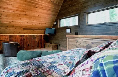 a bedroom with a bed in a room with wooden walls at 9 Boot's Haven in North Wawona