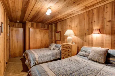 two beds in a room with wooden walls at 17B Tylers Timber Lodge in Wawona