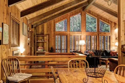 a living room with a table and some windows at 17B Tylers Timber Lodge in Wawona