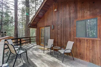 a wooden cabin with chairs and a table on a deck at 17B Tylers Timber Lodge in Wawona