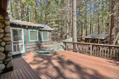 a small cabin on a wooden deck in the woods at 95R The Little Creek Cabin in Wawona